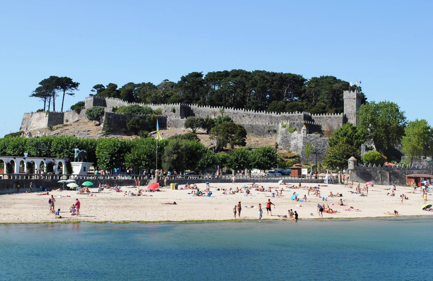 Ribeira beach in Baiona with the walls and pine woods of Monterreal fortress behind