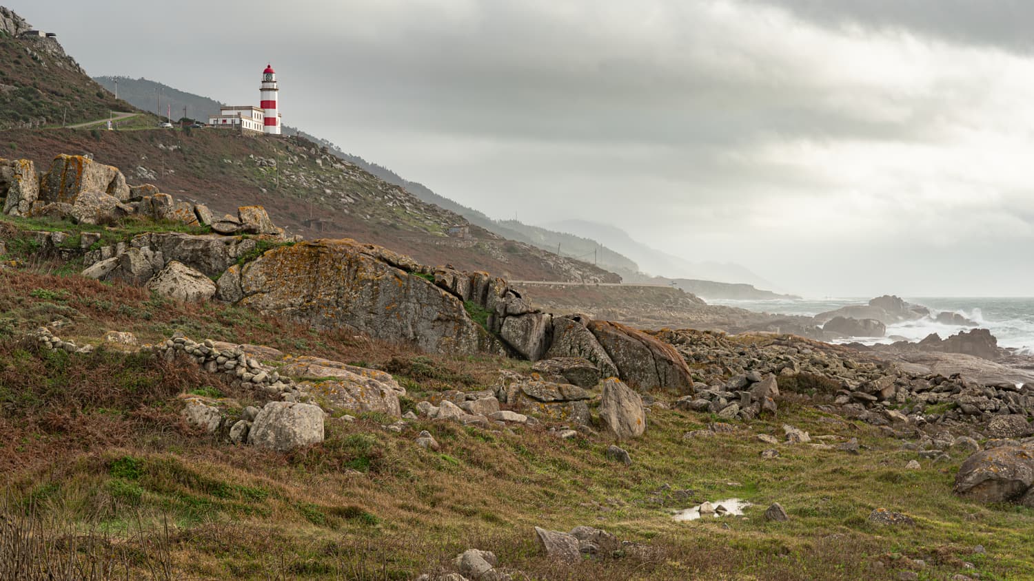 The red-and-white Cabo Silleiro lighthouse on a rocky hillside above the Atlantic