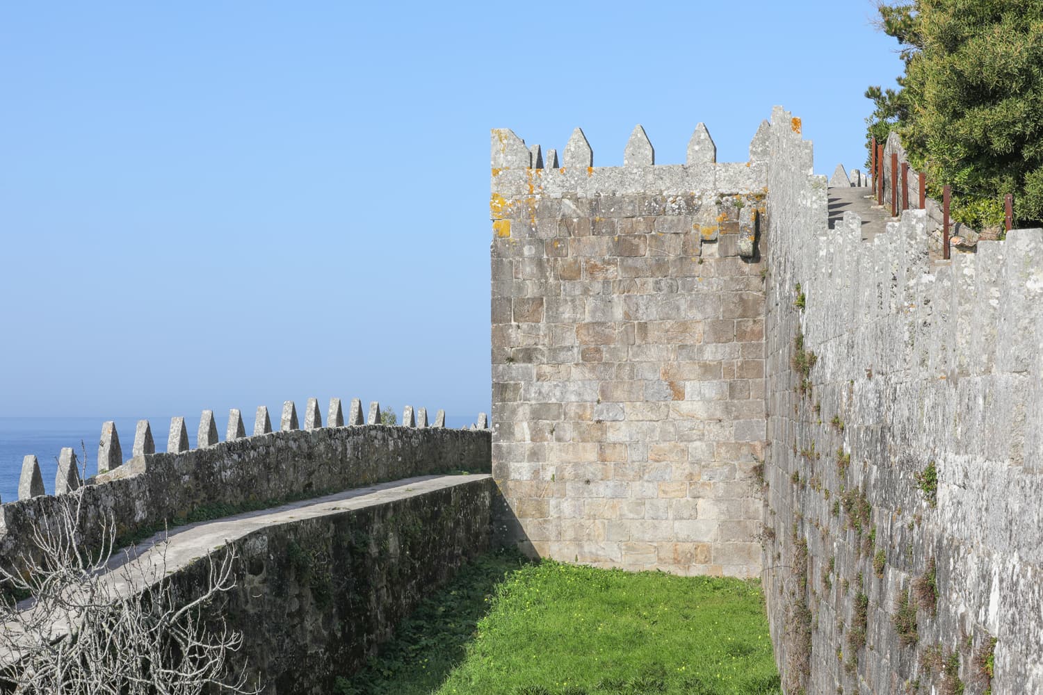Crenellated granite walls and a square tower of Monterreal fortress above the sea in Baiona