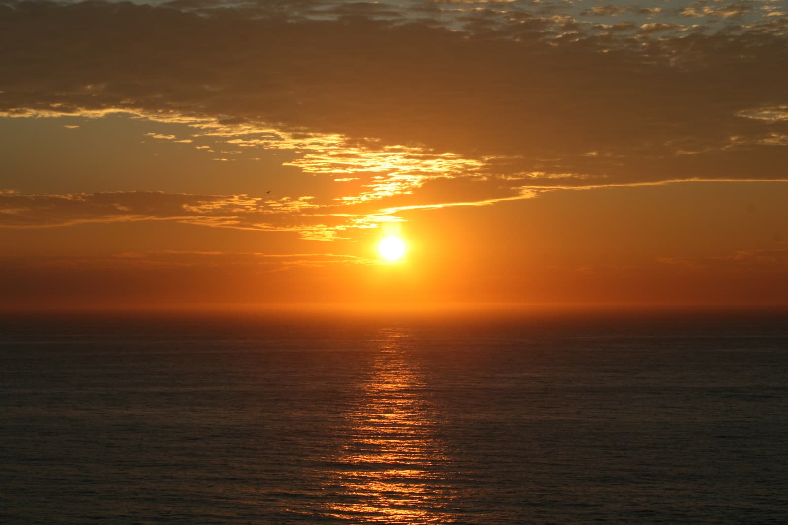 The sun setting into the Atlantic behind the silhouette of Cabo Silleiro