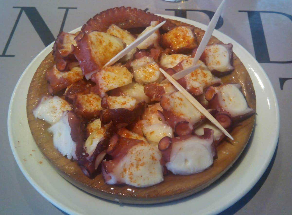 A wooden plate of Galician-style octopus with paprika and olive oil