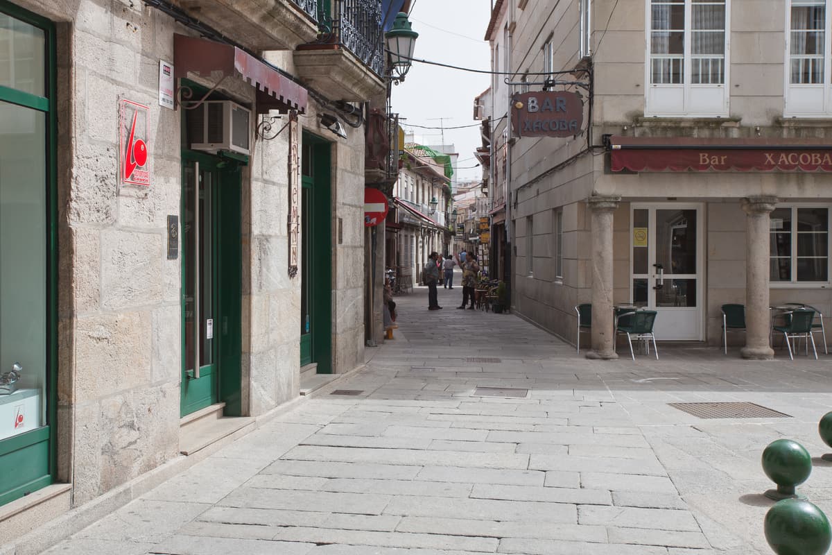 A granite-paved lane with arcades and glazed balconies in Baiona’s old town